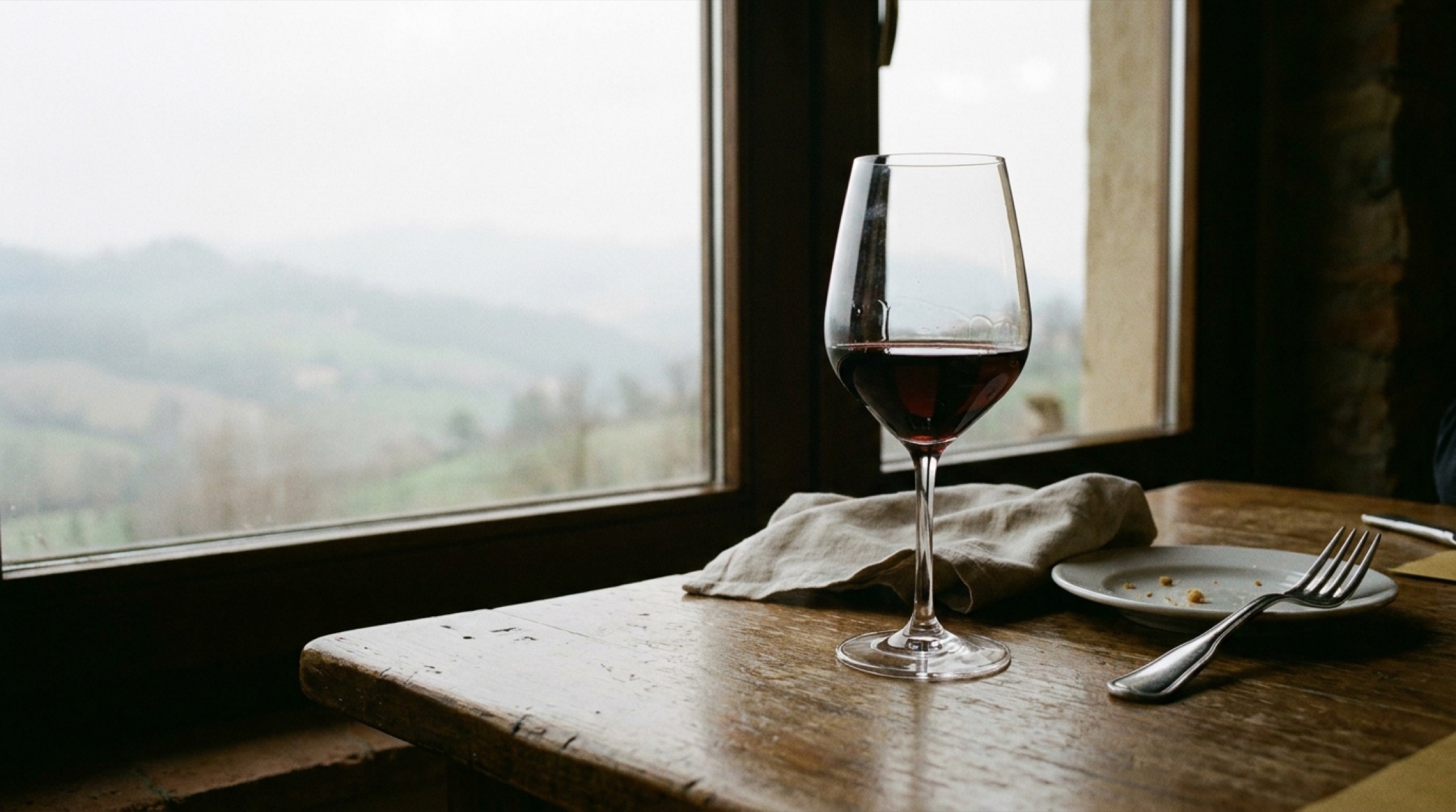 Piemonte tepelerinde sonbahar sisindeki Nebbiolo bağları ve uzakta Alba şehri silueti