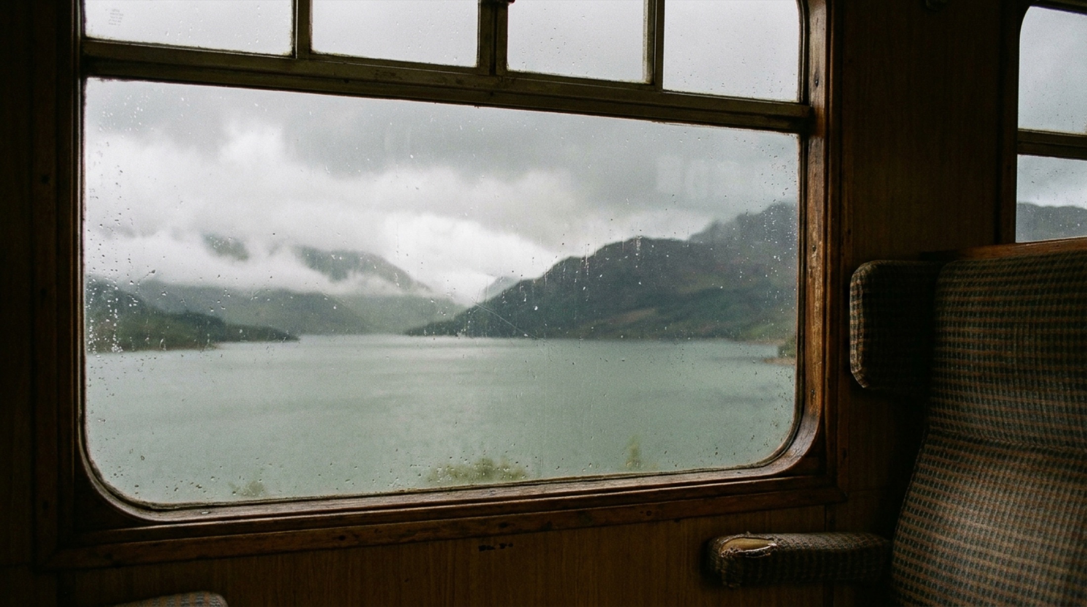Royal Scotsman tren penceresinden İskoçya'nın sisli loch'una ıslak cam üzerinden bakış