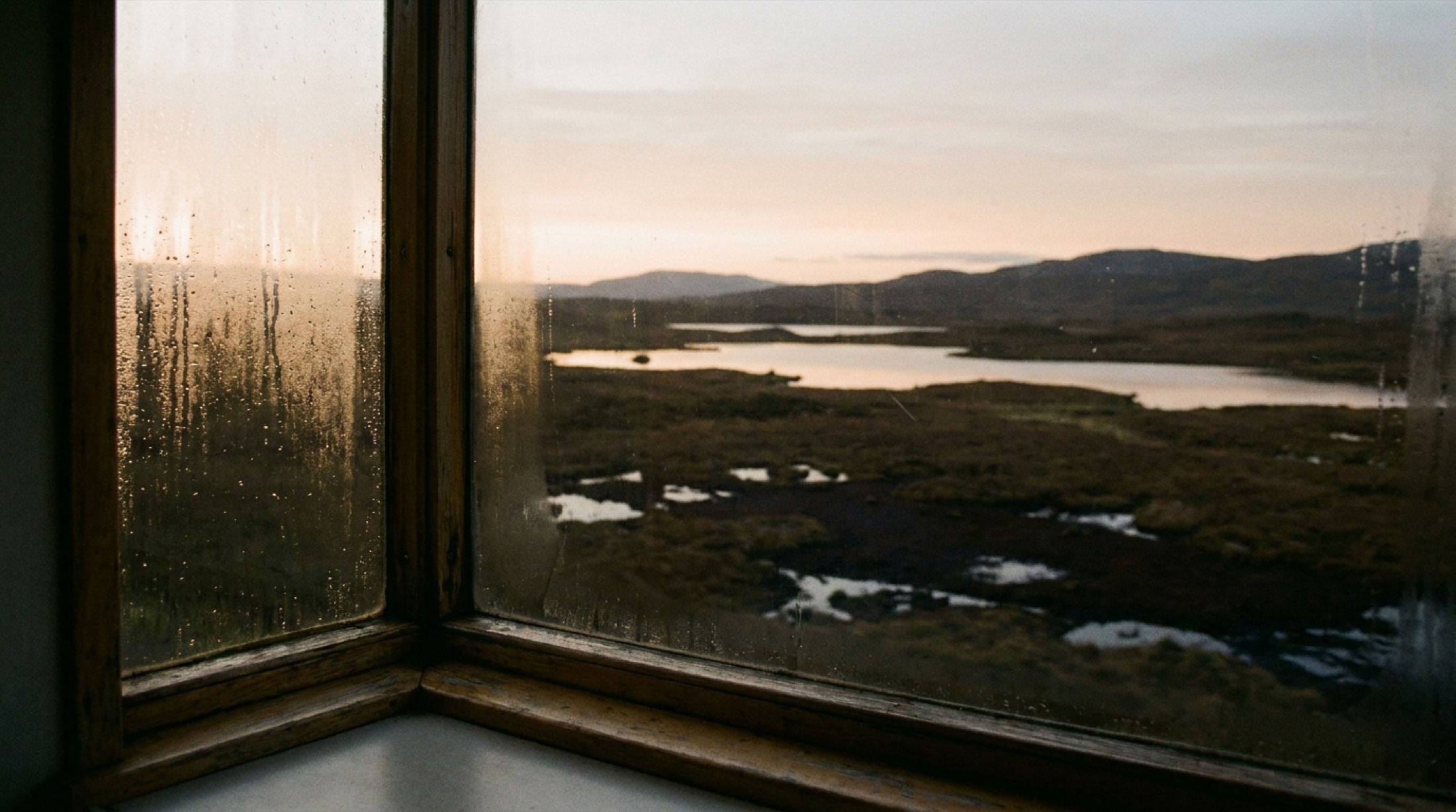 Caledonian Sleeper'ın penceresinden şafak vakti Rannoch Moor manzarası — turba bataklığı ve soluk gün ışığı