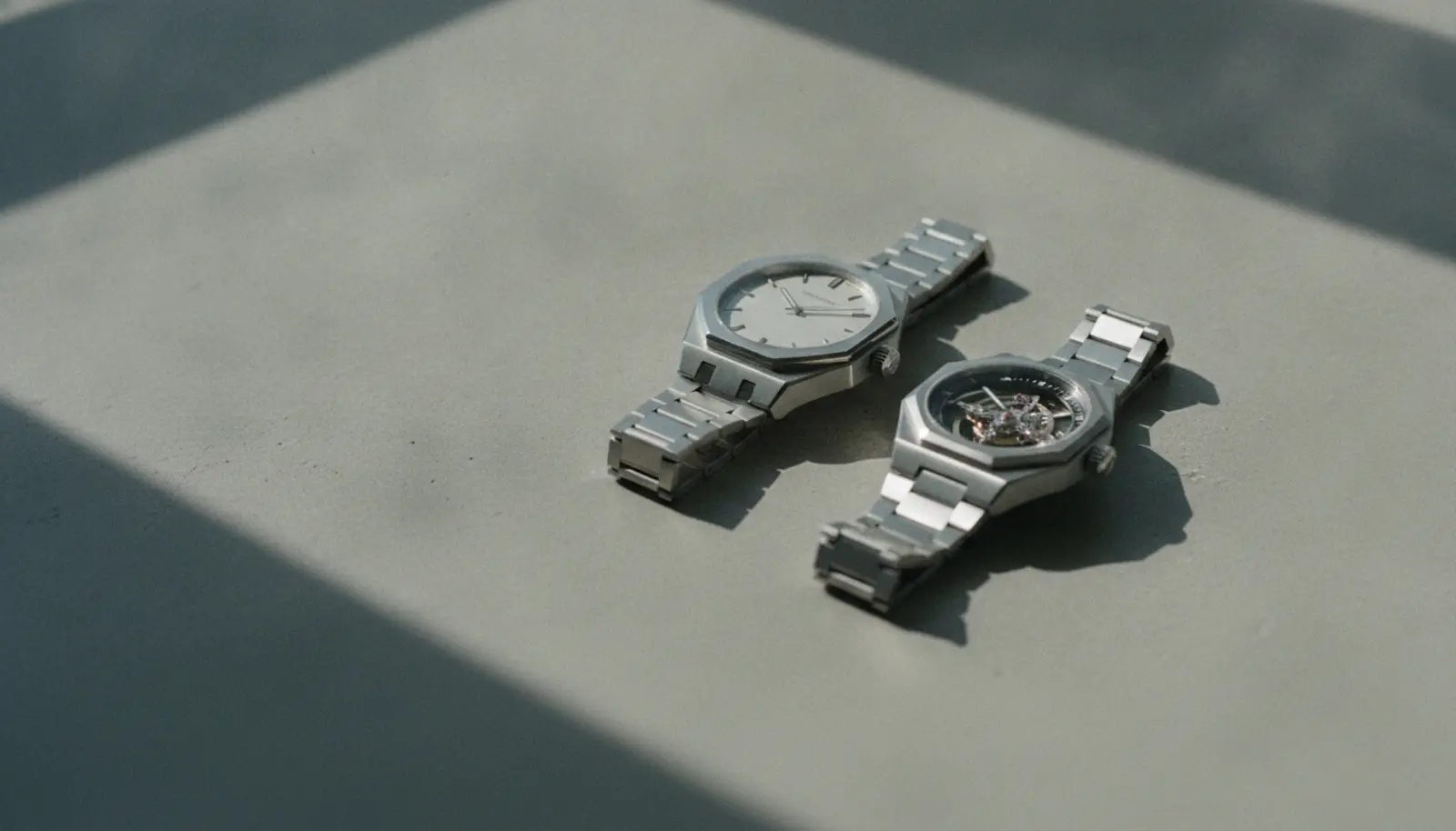 Czapek Antarctique Tourbillon ve Zenith Defy Revival A3643 saatleri beton yüzey üzerinde yan yana, doğal yan ışıkla