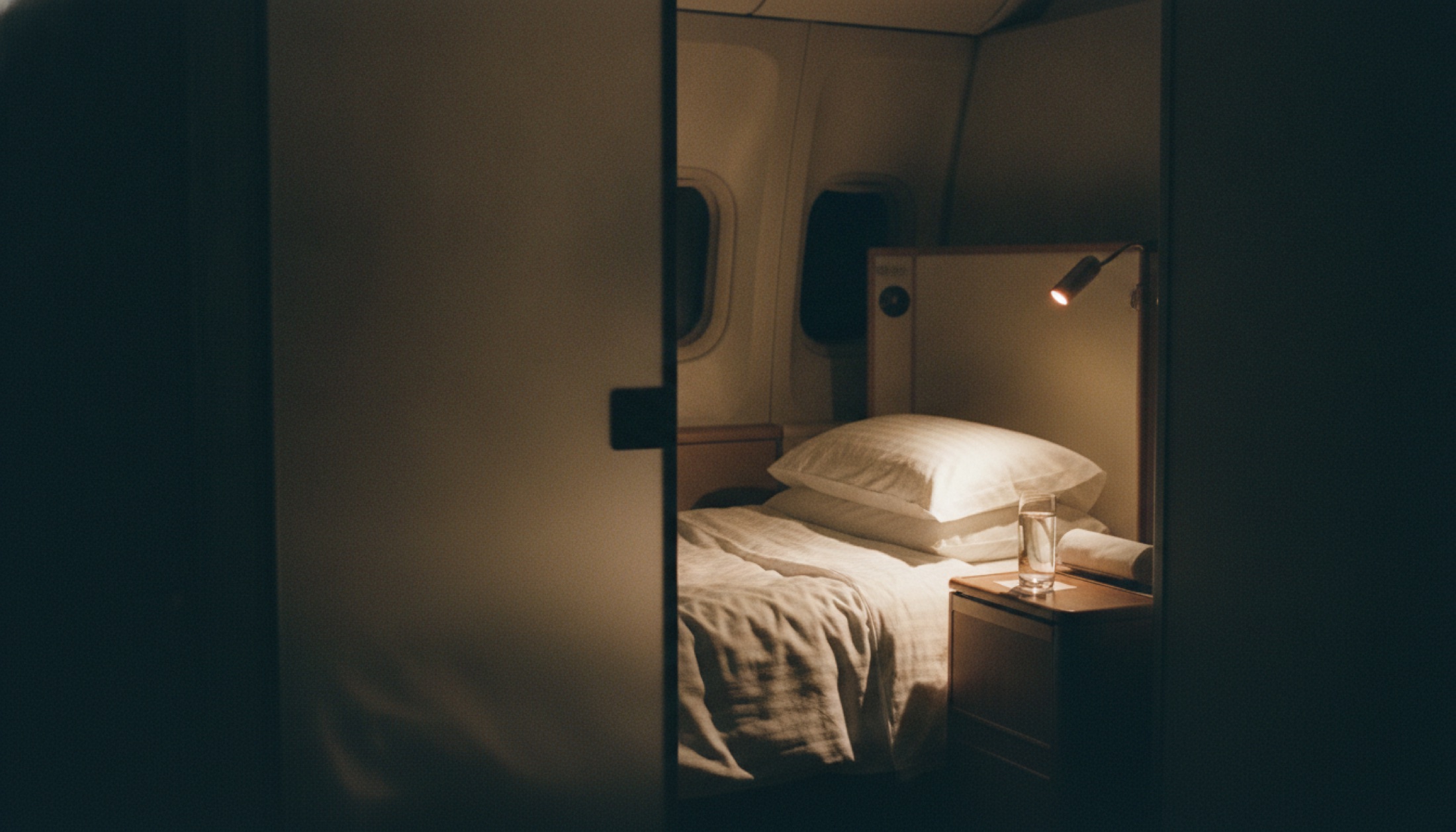 Emirates 777 Game Changer first class süiti — kapalı kapı, açılmış yatak modu, gece uçuşu