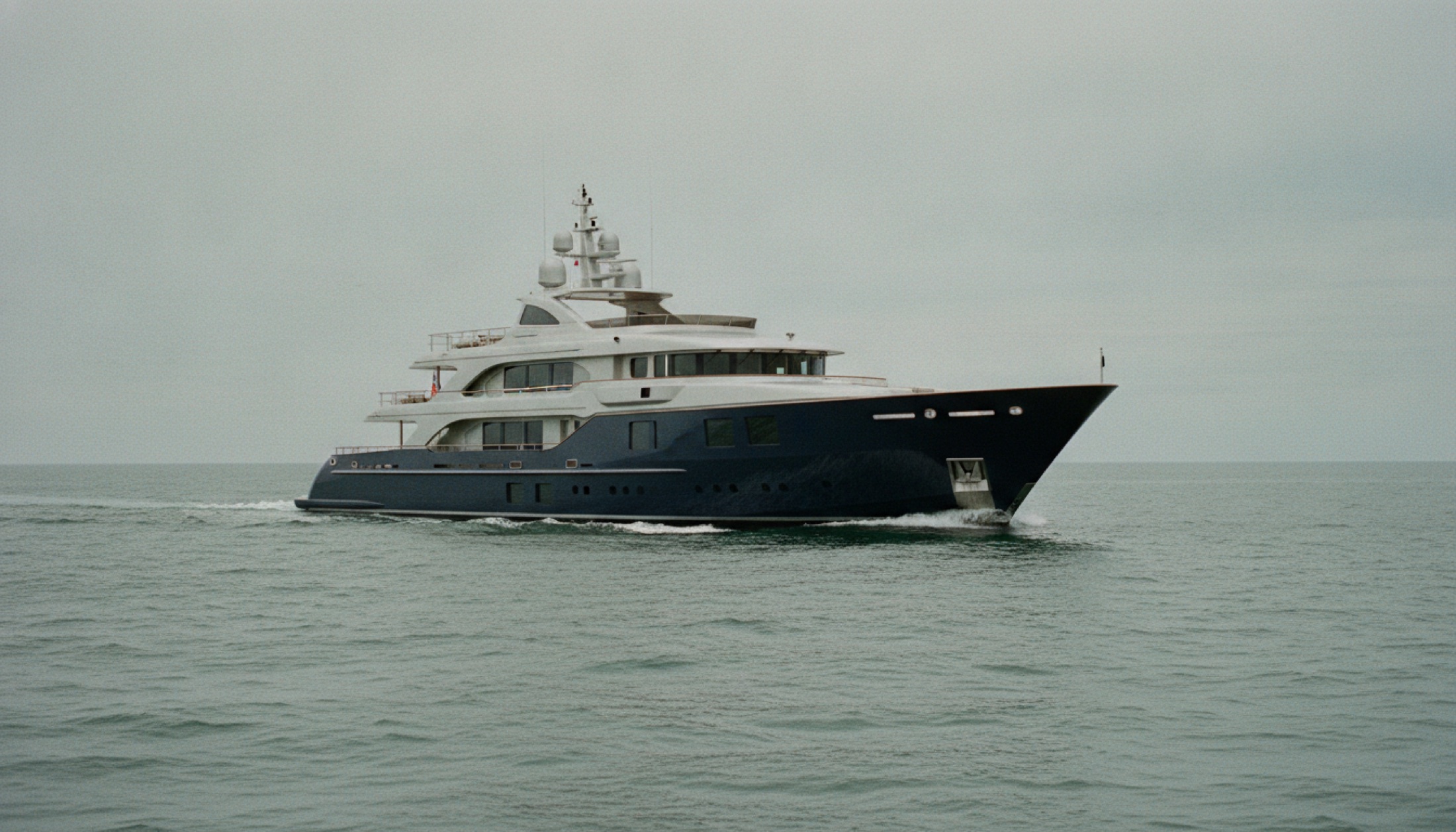 Feadship Project 1014 motor yatının lacivert çelik gövdesi Kuzey Denizi'nde ilerliyor, alüminyum üst yapı bulutlu ışıkta mat bir parlaklık taşıyor
