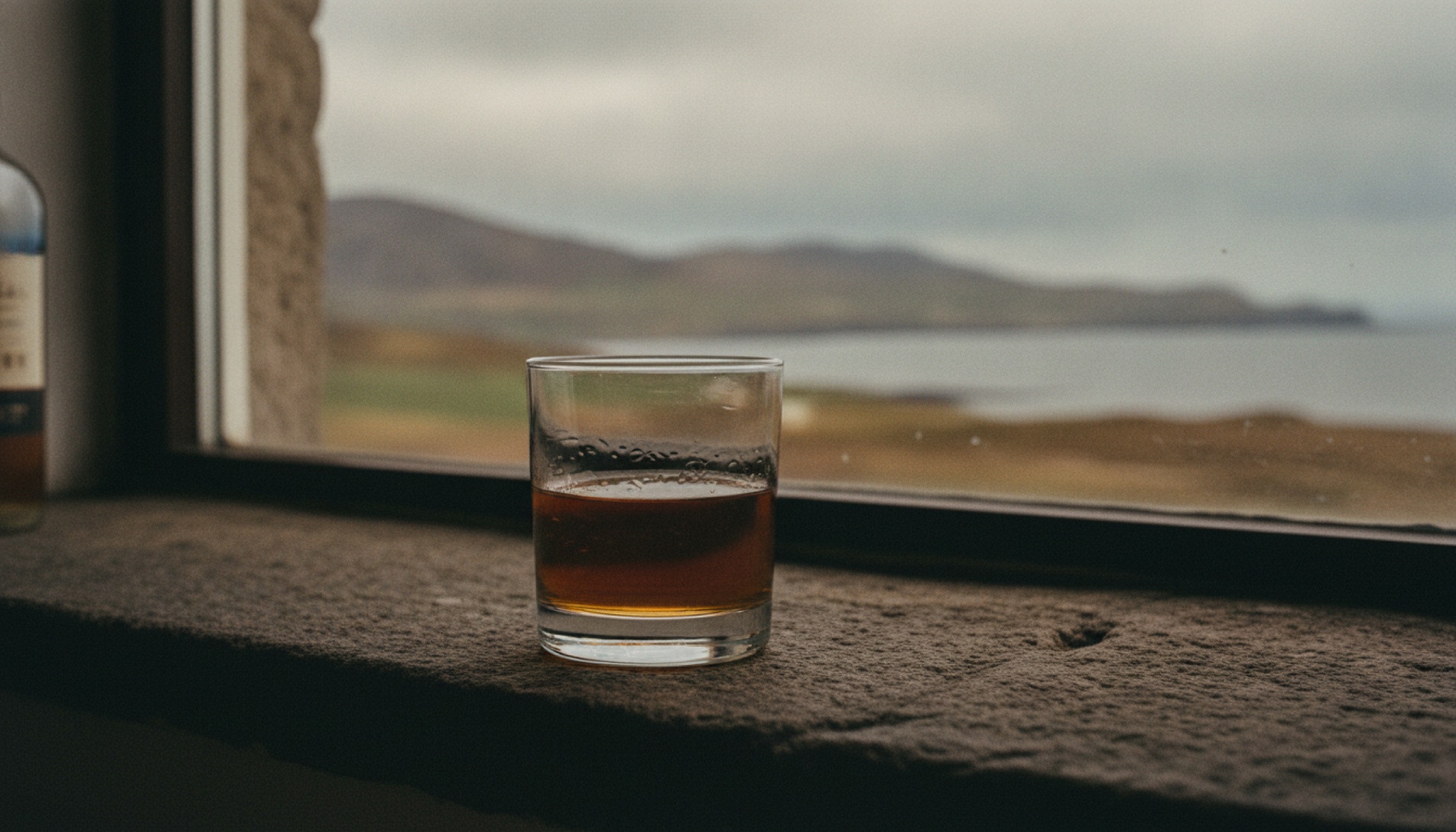 InchDairnie KinGlassie Double Matured — Fife'ın turbalı Lowland single malt'ından bir kadeh, taş pervaz üzerinde.