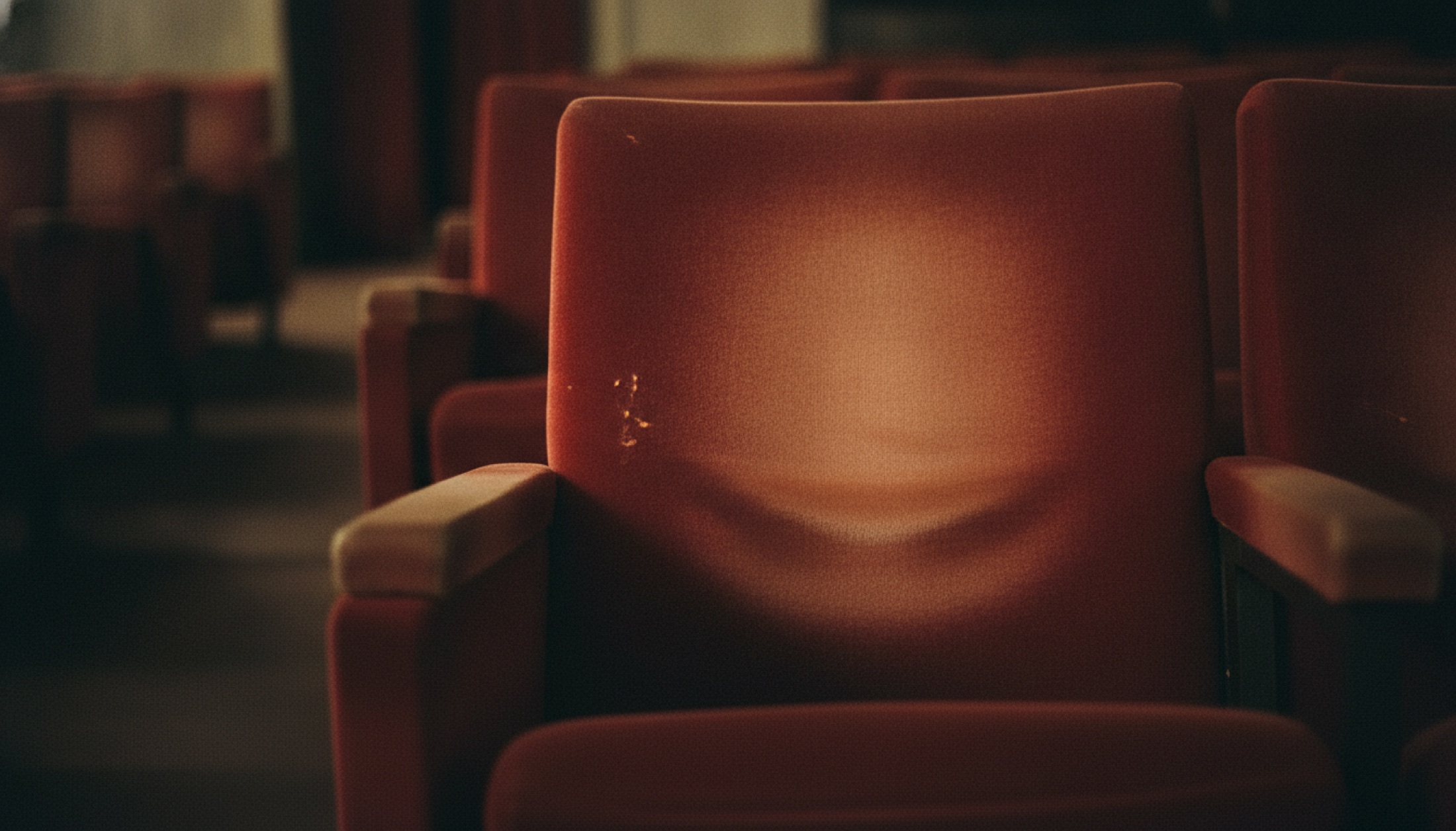 Boş sinema koltuğu, kırmızı kadife döşeme, film ışığının yansıması