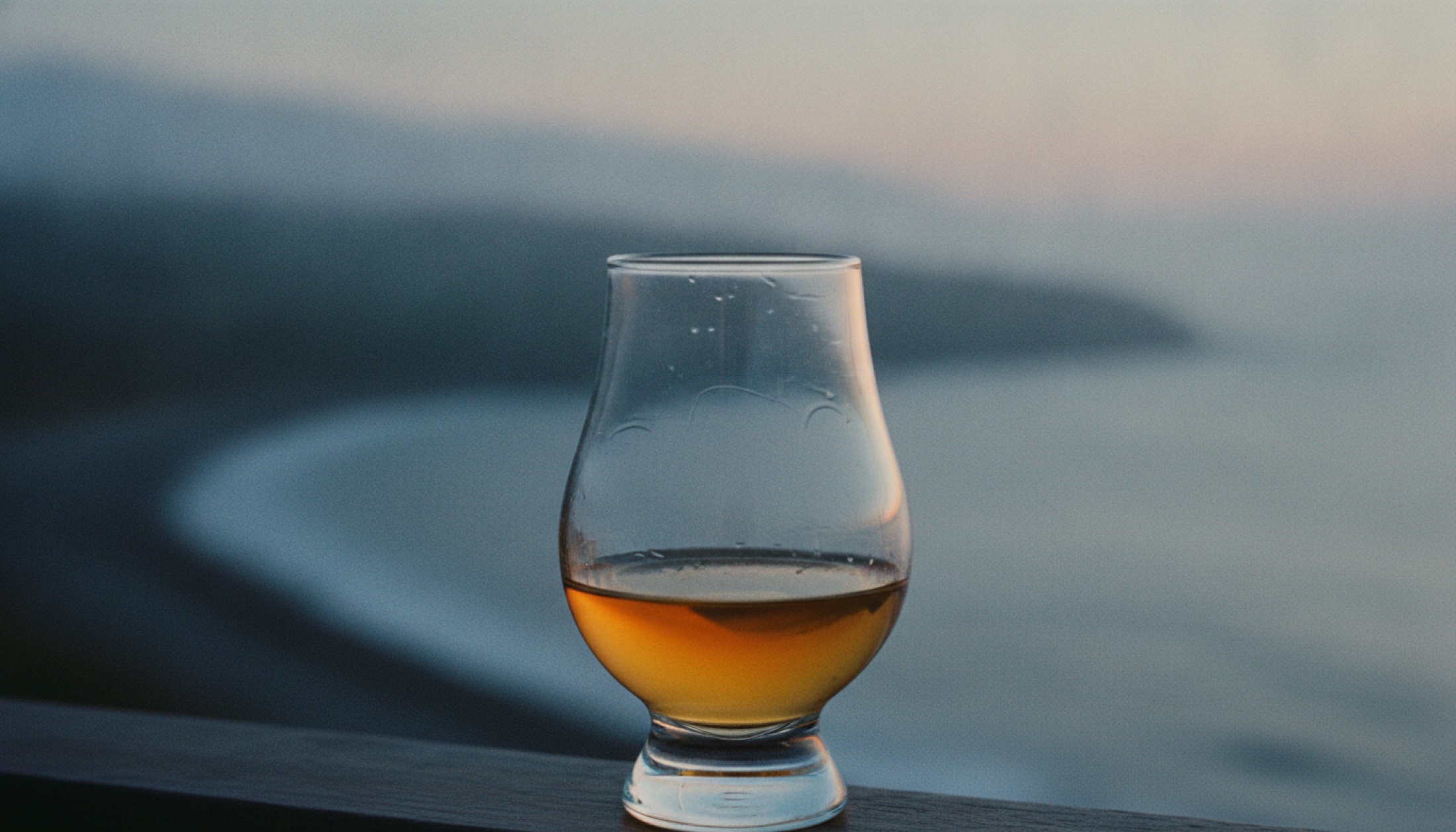 Ex-bourbon fıçısında dinlenmiş Islay single malt viskisi, Glencairn kadehinde, sisli bir kıyı arka planıyla