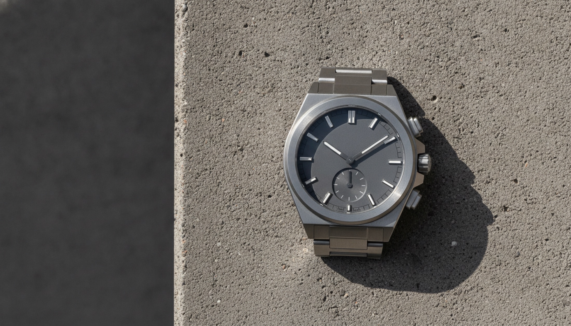 Laurent Ferrier Sport Traveller titanyum dual-time saat, beton yüzey üzerinde yan ışıkla çekilmiş editoryal fotoğraf