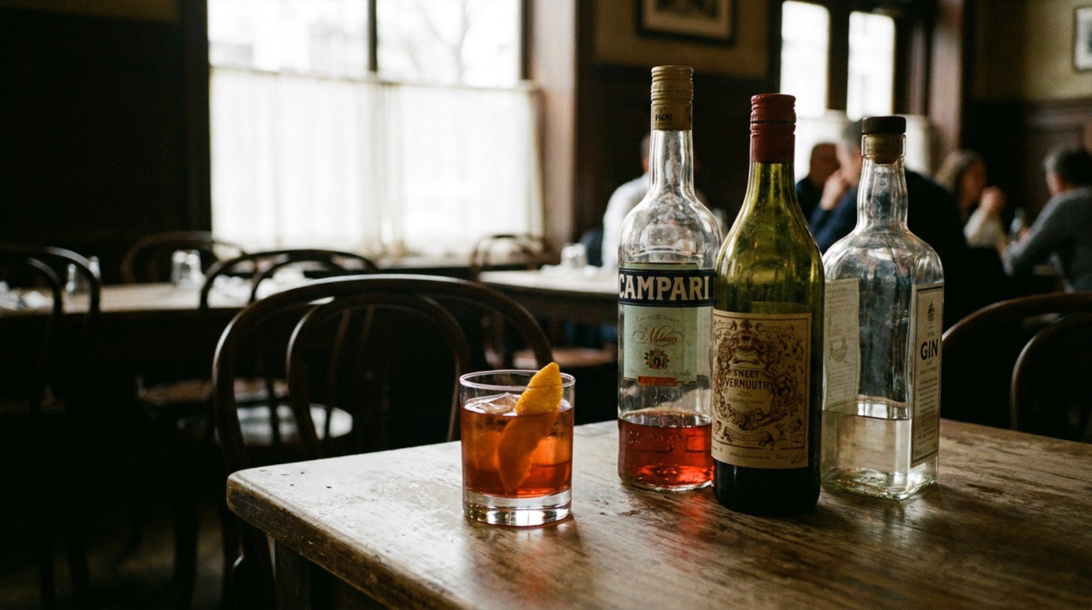 Turuncu portakal dilimiyle süslenmiş kırmızı Negroni kokteyli, buz dolu kayadan kütük bardakta